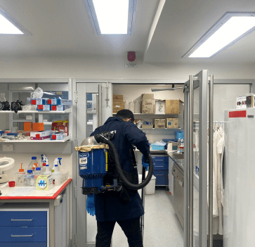 Laboratory cleaners spraying down surfaces inside bio-tech laboratory