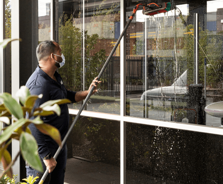 Man cleaning large windows of industrial building