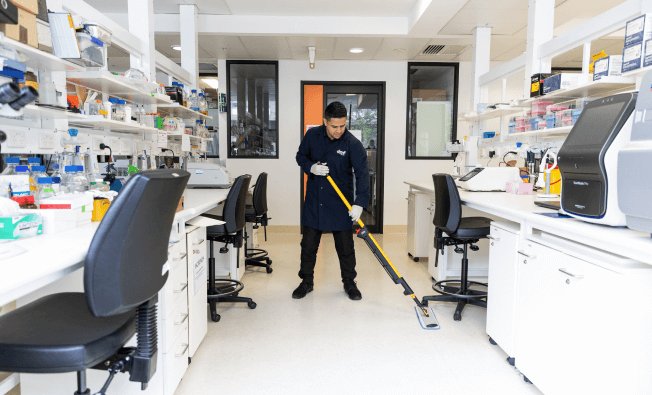 Team of professional laboratory cleaners cleaning floor of high-tech lab